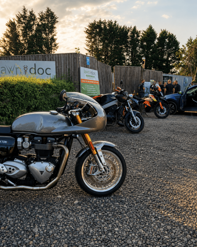 Triumph motorcycle parked at Buckovers Bike Night with other motorcycles and visitors in the background.